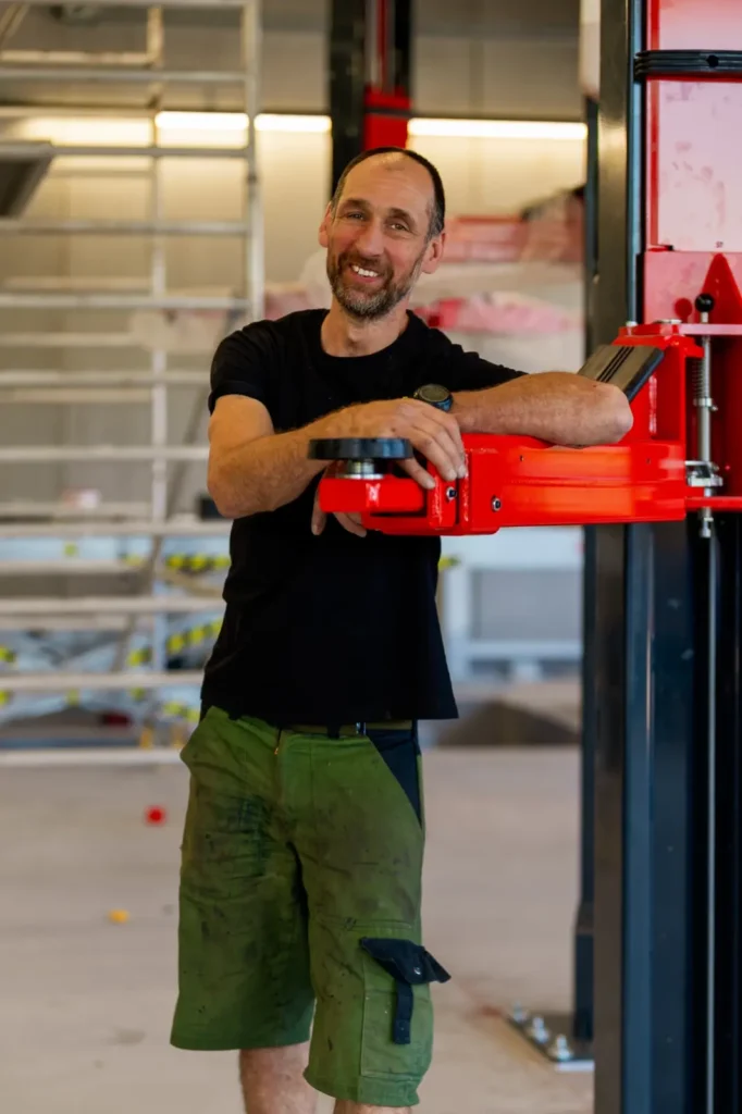 Lackierer Hans-Peter in der GEARHEADS Werkstatt an einer roten Hebebühne